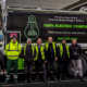 Photo of electric refuse collection vehicle and the waste management team of six people pictured outside the Ziff Buildong at University of Leeds