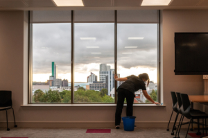 Cleaner cleaning window ledge with a view of the cityscape