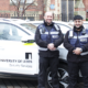 Security Services standing outside the Great Hall building, featuring the electric vehicle