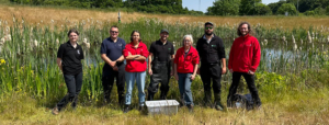 James Wright from the Estates team, people from the Environment Agency and academics from the School of Biology stood in front of Bodington pond.